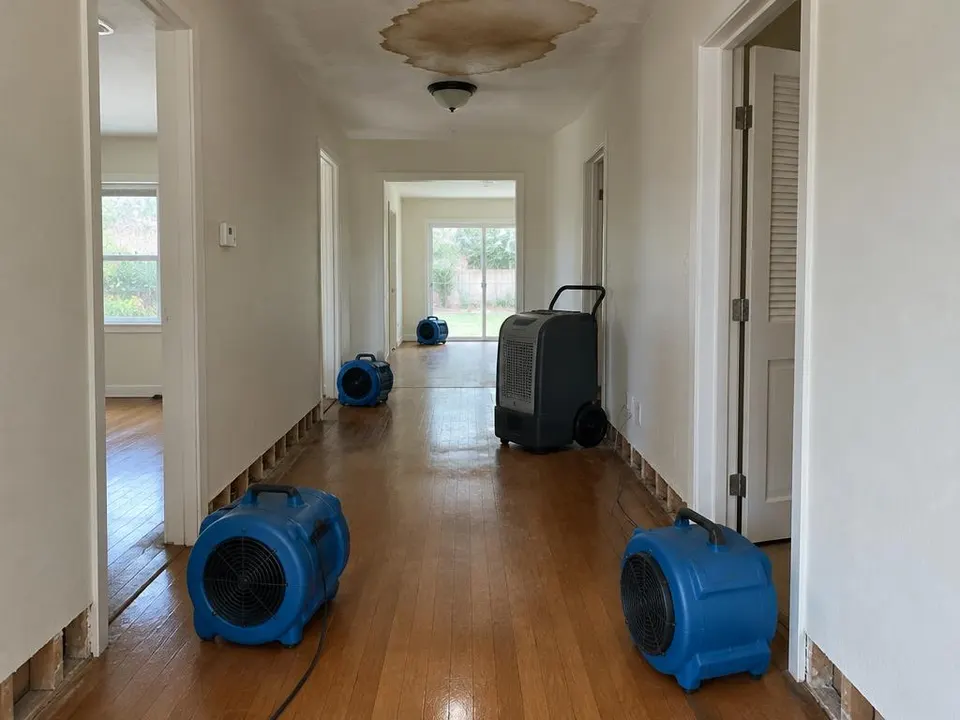 Generated illustration of air movers and a dehumidifier drying a hallway with a ceiling water stain
